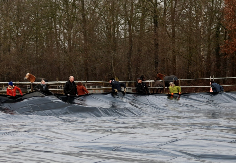 12-02-26 Vrijwilligers helpen bij uitrollen folie nieuwe buitenbak manege De Driesporen: Foto: Freerk Boskers Fotografie